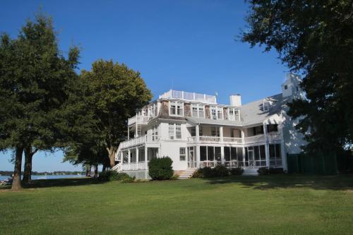 a large white house sitting on top of a lush green field at Wades Point Inn on the Bay in Saint Michaels