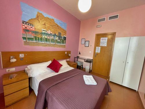 - une chambre avec un lit et une peinture murale dans l'établissement Pensión Alicante San Nicolás, à Alicante