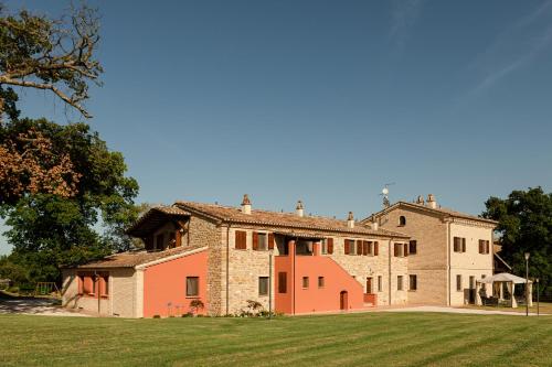 una casa grande con un campo de hierba delante de ella en Agriturismo Casale San Lorenzo, en San Lorenzo in Campo