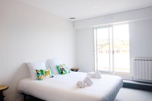 Cette chambre comprend un lit blanc et une grande fenêtre. dans l'établissement Magnifique appartement, en hyper centre, avec terrasse et place de parking, à Biarritz