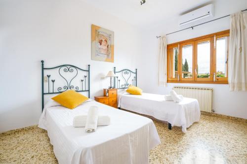 a bedroom with two beds with white sheets and yellow pillows at Villa Son Valentí in Sa Pobla