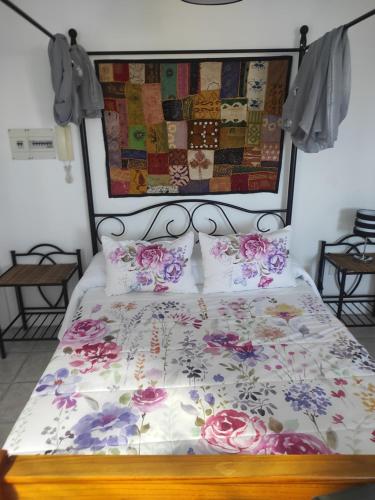 - un lit avec une couette et des oreillers à fleurs dans l'établissement Ático Arinaga con vistas , jacuzzi , terraza y barbacoa, à Arinaga