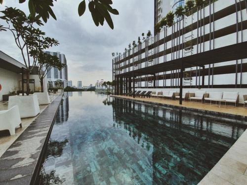 - une grande piscine dans un bâtiment avec des chaises blanches dans l'établissement Vivo Soho Suite @ Mid Valley Old Klang Road KL, à Kuala Lumpur