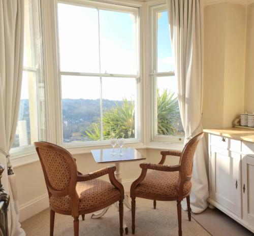a kitchen with two chairs and a table in front of a window at West Hill Retreat Edwardian Balcony Grand Ensuite with Room Served Breakfast & Free Offstreet Parking in Hastings
