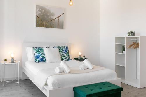 a white bedroom with a white bed with a green stool at Calçada 14 in Óbidos