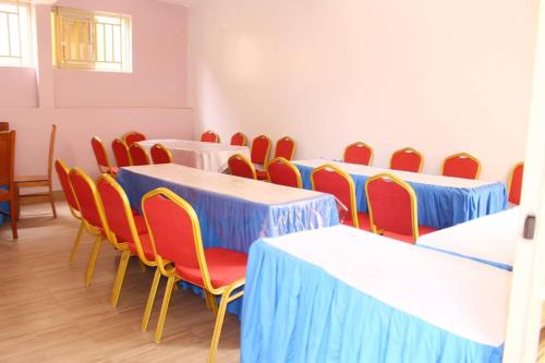 a room with tables and chairs with blue and yellow tables at Fanad Hotel in Gisenyi