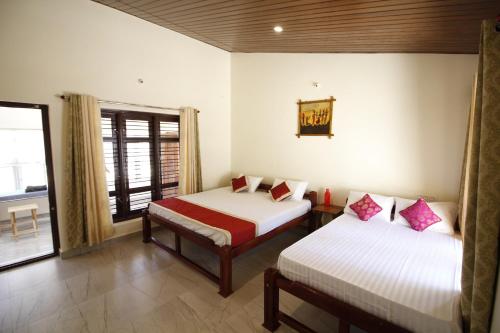 a room with two beds and a window at Meeslu Mane, The Chic HomeStay in Hassan