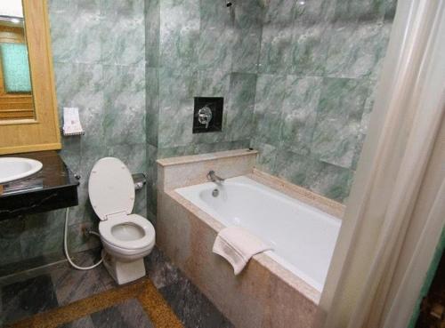 a bathroom with a tub and a toilet and a sink at 13 Coins Tower Hotel Ratchada in Bangkok