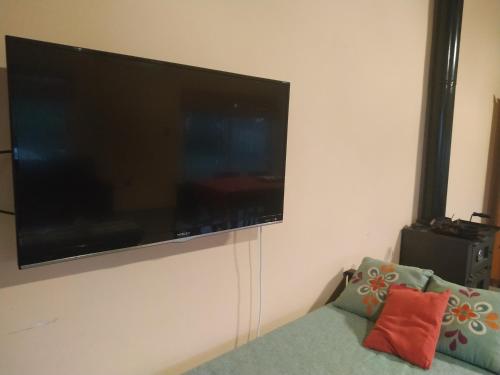 TV de pantalla plana colgada en una pared con sofá en LA QUINTA DE LOLI, en San Pedro