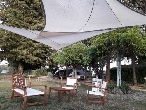 a group of chairs sitting under a white umbrella at Agriturismo Bio Pian Dei Casali in Saturnia