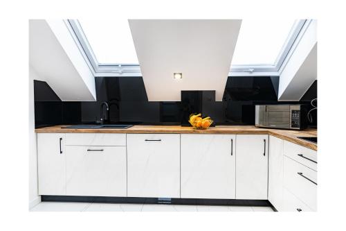 a kitchen with white cabinets and skylights at Apartament Kornelia in Gołdap