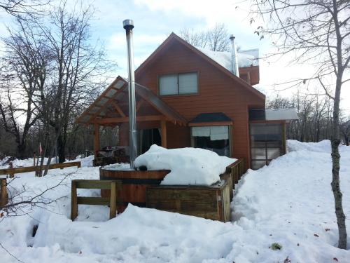 a house with a hot tub in the snow at Cabañas Maroni in Las Trancas