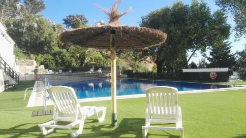 un grupo de sillas y una sombrilla junto a una piscina en La Casita de Betania, en Benaocaz