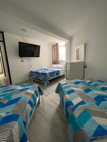 a hotel room with two beds and a flat screen tv at TACNA APART in Tacna