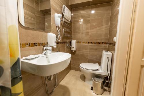 
a bathroom with a toilet, sink, and mirror at Palanga Camping Compensa Hotel in Palanga
