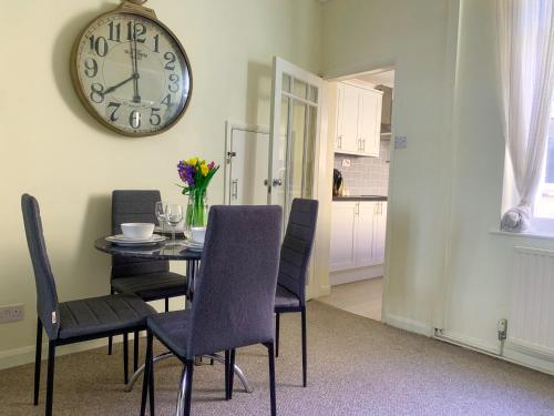 a dining room with a table and a clock on the wall at Park Crescent Lodge - Quaint Victorian Home With Free Parking in York