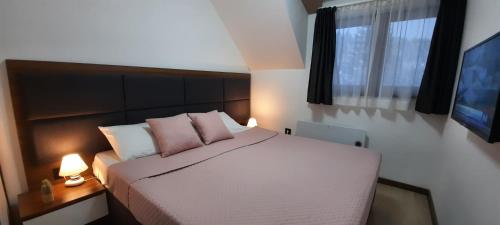 a bedroom with a bed with pink pillows and a window at Apartman M&S - Zoned 2 in Kopaonik