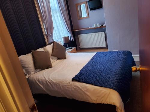 a bedroom with a bed with a blue blanket on it at the cumbrian hotel in Blackpool