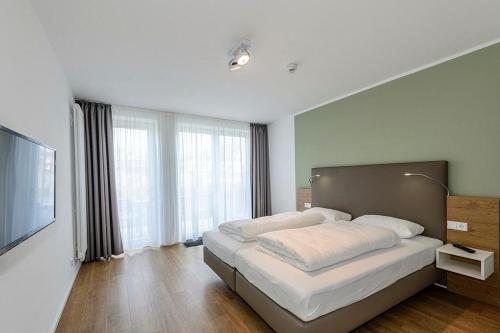 ein Schlafzimmer mit einem großen Bett und einem großen Fenster in der Unterkunft Apartmentvilla Anna See Apartmentvilla Anna See 1-11 in Langeoog