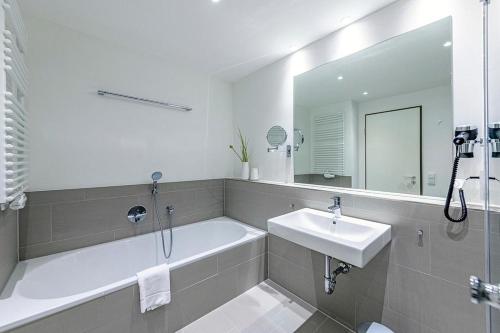 ein Badezimmer mit Badewanne, Waschbecken und Spiegel in der Unterkunft Apartmentvilla Anna See Apartmentvilla Anna See 1-11 in Langeoog