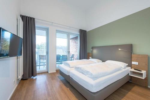 a bedroom with a large bed and a flat screen tv at Apartmentvilla Anna See Apartmentvilla Anna See 3-08 in Langeoog