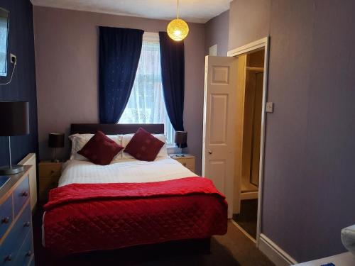 a bedroom with a bed with a red blanket and a window at the cumbrian hotel in Blackpool