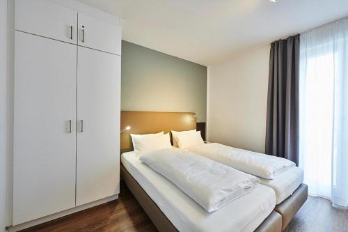 ein Schlafzimmer mit einem großen Bett mit weißer Bettwäsche in der Unterkunft Deichhäuser Anna Küste Deichhäuser Anna Küste 4-20 in Bensersiel