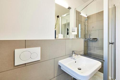 ein weißes Badezimmer mit Waschbecken und Spiegel in der Unterkunft Deichhäuser Anna Küste Deichhäuser Anna Küste 4-20 in Bensersiel