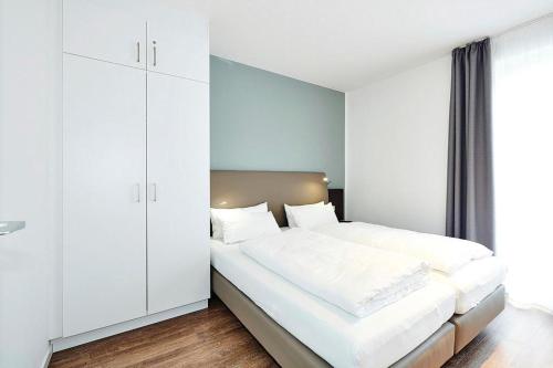 ein Schlafzimmer mit einem großen Bett mit weißen Schränken in der Unterkunft Deichhäuser Anna Küste Deichhäuser Anna Küste 4-10 in Bensersiel