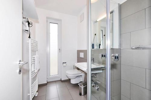 ein weißes Badezimmer mit Toilette und Waschbecken in der Unterkunft Deichhäuser Anna Küste Deichhäuser Anna Küste 4-10 in Bensersiel
