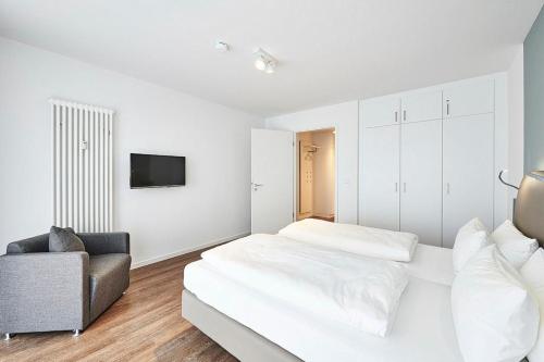 ein weißes Schlafzimmer mit einem Bett und einem Stuhl in der Unterkunft Deichhäuser Anna Küste Deichhäuser Anna Küste 4-31 in Bensersiel