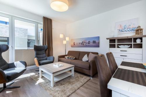 ein Wohnzimmer mit einem Sofa, Stühlen und einem Tisch in der Unterkunft Aparthotel Ostseeallee Aparthotel Ostseeallee 2-12 in Boltenhagen