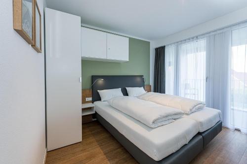 ein Schlafzimmer mit einem großen Bett mit weißer Bettwäsche in der Unterkunft Deichhäuser Anna Küste Deichhäuser Anna Küste 8-23 in Bensersiel