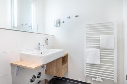 ein weißes Badezimmer mit Waschbecken und Spiegel in der Unterkunft Godewindpark Travemünde Godewindpark Travemünde 1-07 in Travemünde