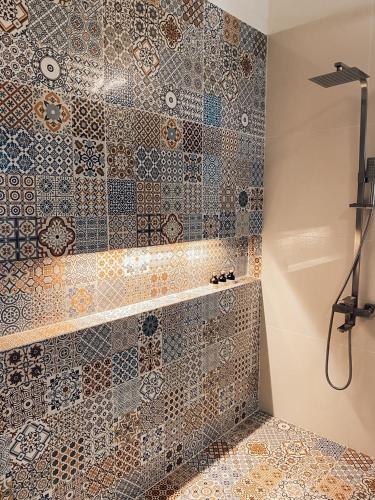 a bathroom with a shower with mosaic tiles on the wall at Villa Lagoonscape in Negombo