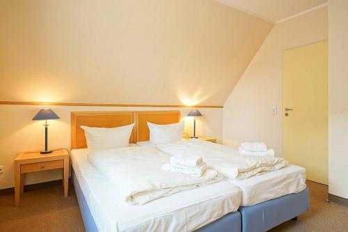 ein Schlafzimmer mit einem großen weißen Bett mit Handtüchern darauf in der Unterkunft Hus Inselkieker Hus Inselkieker 219 in Schillig