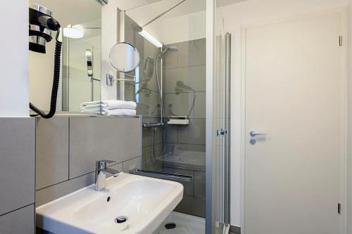 ein Badezimmer mit Waschbecken, Dusche und Spiegel in der Unterkunft Deichhäuser Anna Küste Deichhäuser Anna Küste 1-30 in Bensersiel