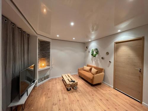 a living room with a couch and a television at Casa Jaubertie - Appartement cosy et chaleureux refait à neuf - HYPER CENTRE BRIVE in Brive-la-Gaillarde