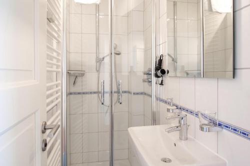 een witte badkamer met douche en wastafel bij Haus Panorama Haus Panorama 12 in Wangerooge