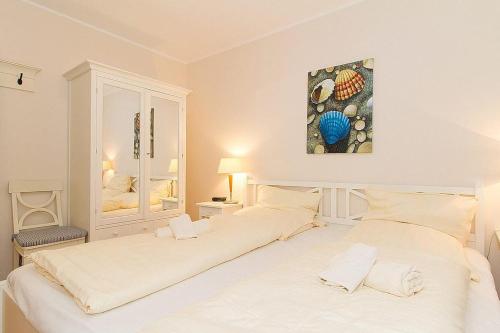 twee bedden in een witte slaapkamer met een schilderij aan de muur bij Urlaubsräume am Meer Urlaubsräume am Meer 3-13 in Fulgen
