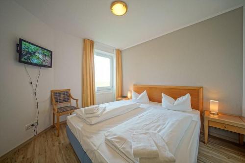 Un dormitorio con una gran cama blanca y una ventana en Hus Inselkieker Hus Inselkieker 220, en Schillig