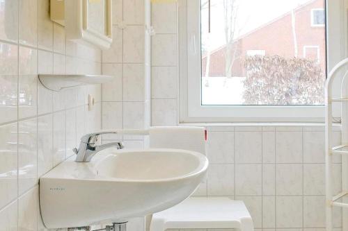 een witte badkamer met een wastafel en een raam bij Urlauberdorf Urlauberdorf 43a in Boltenhagen