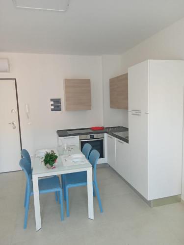 uma pequena cozinha com uma mesa e duas cadeiras azuis em Appartamento Pleiadi em Finale Ligure