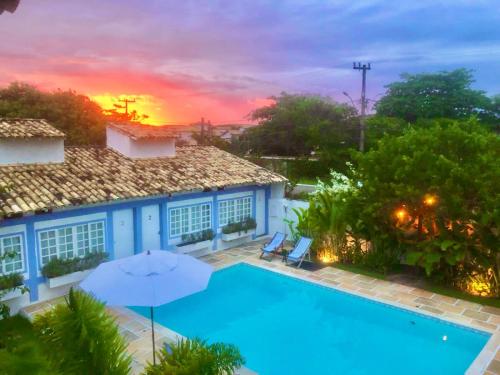 a house with a swimming pool and an umbrella at Pousada Manaaki in Búzios