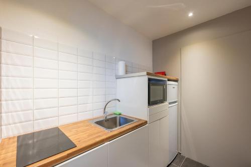 a kitchen with a sink and a microwave at Hotel Fi'Lin in Machelen