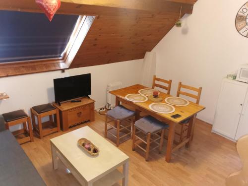 a living room with a table and a tv at Le petit Chalet Luchonnais in Luchon