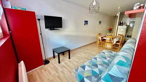 Una sala de estar con un sofá y un televisor en la pared. en Résidence Le mont Dore 2 étoiles, en Le Mont-Dore