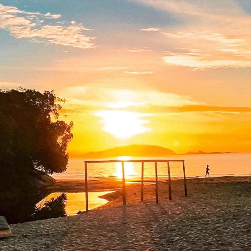 a person walking on the beach at sunset at Pousada Cantinho da Praia in Paraty