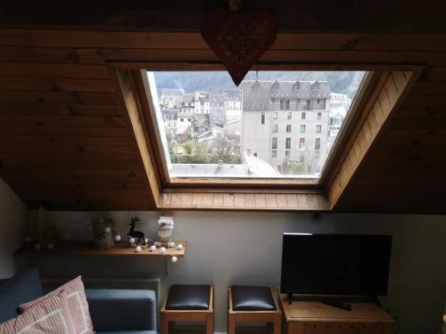 a living room with a large window and a tv at Le petit Chalet Luchonnais in Luchon