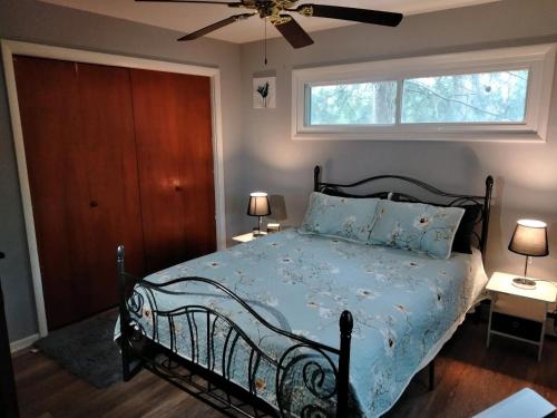 1 dormitorio con 1 cama con edredón azul y ventana en Farmhouse attached apartment, en Old Mill Creek
